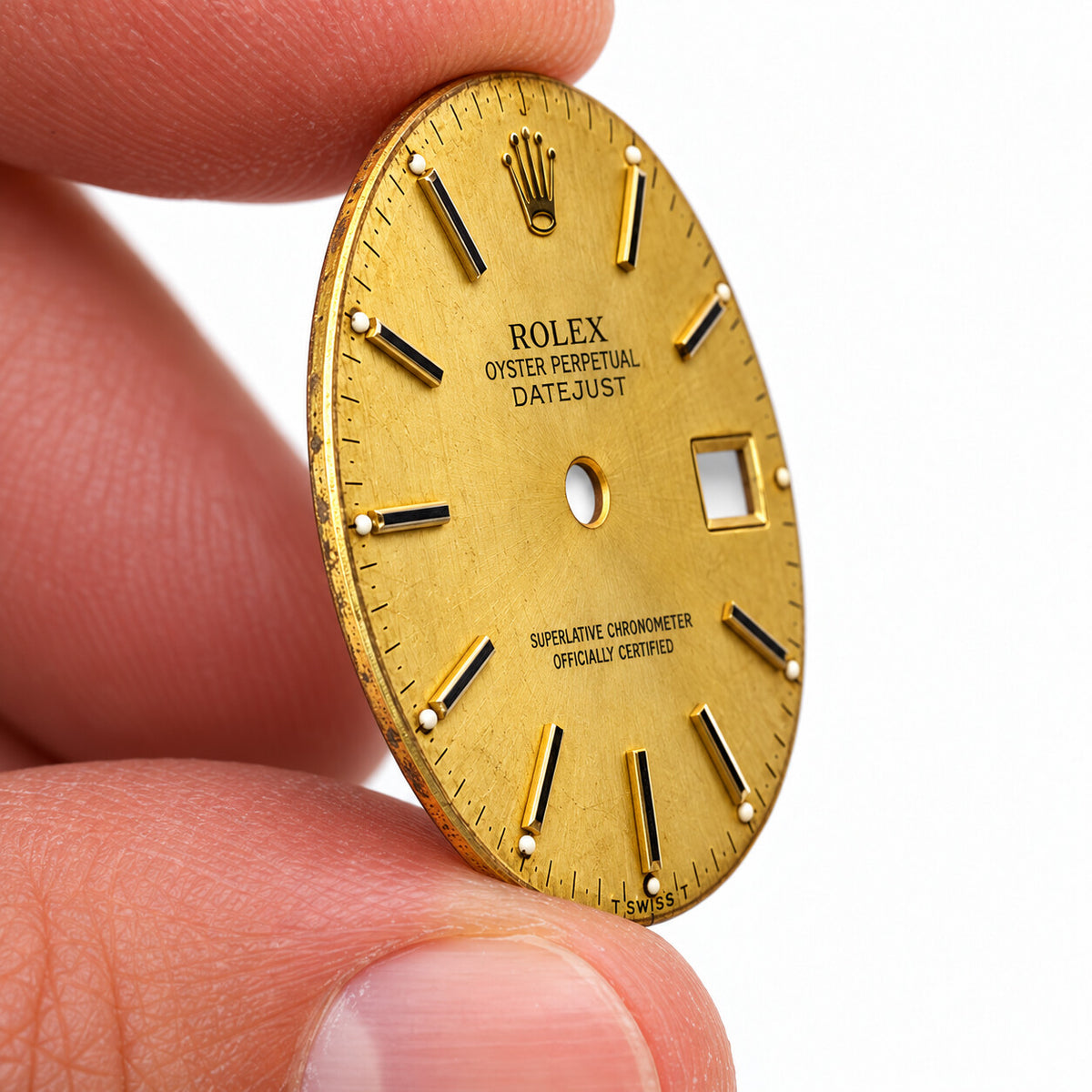 Illustrative side-angle view of champagne Rolex dial held between fingers